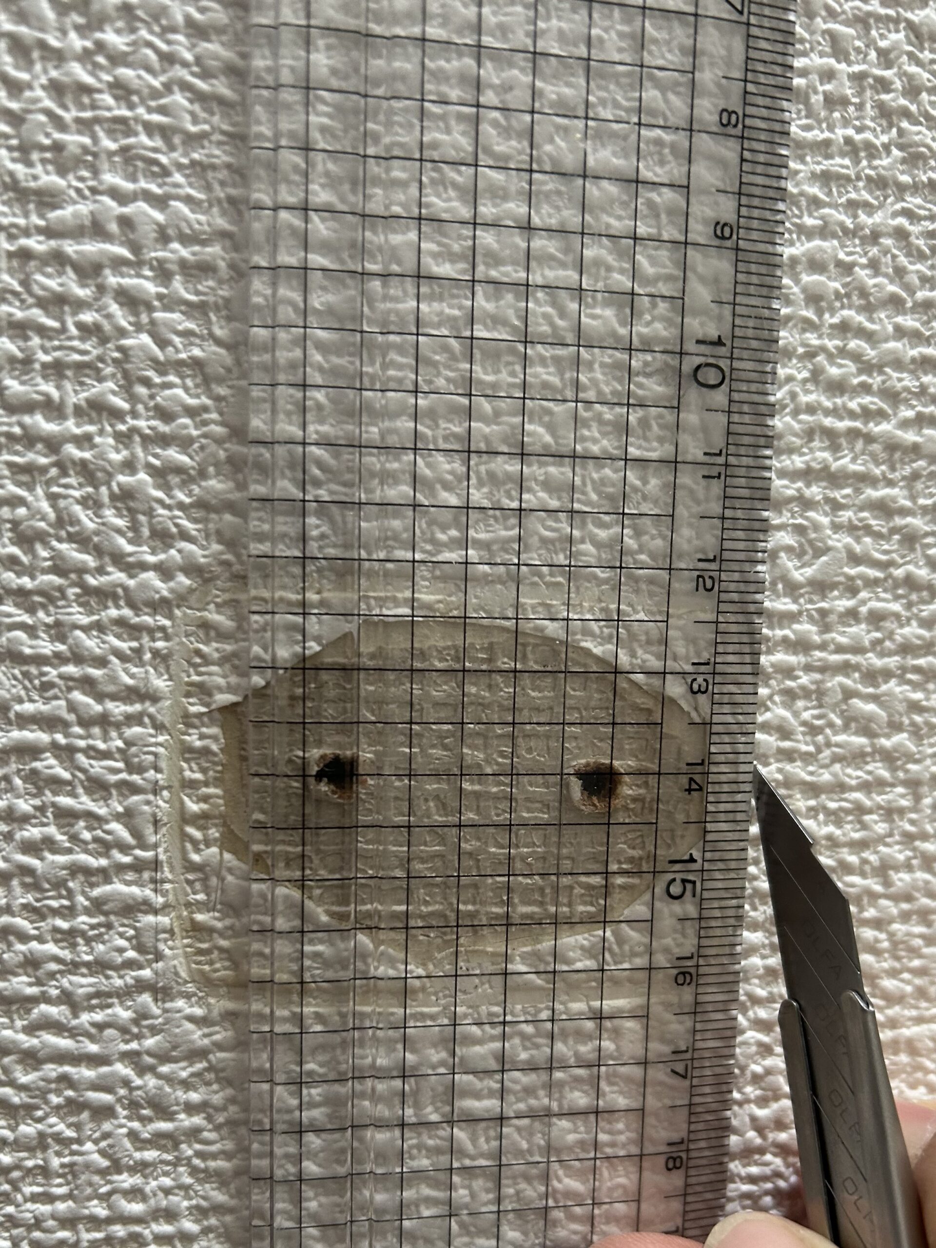 カッターで汚れた壁紙を切り取る