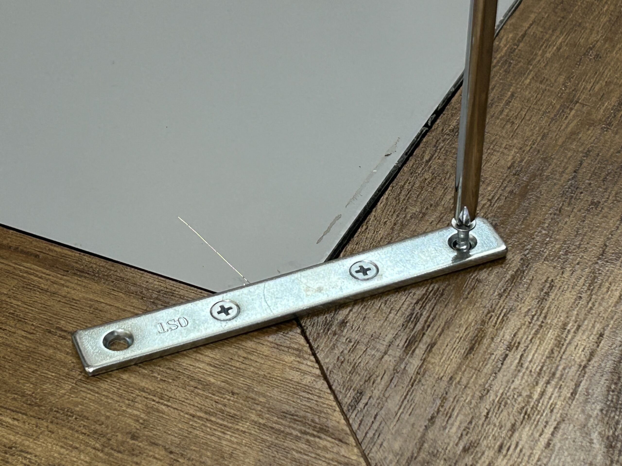 角に金具をビスで固定。鏡の押さえと木枠の補強を兼ねる