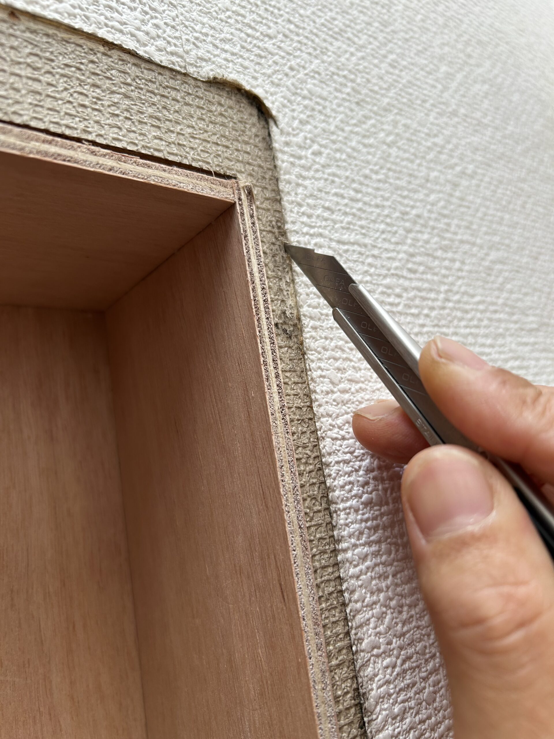 棚の周りの古い壁紙にカッターを入れる